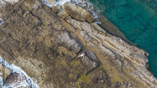 The girl sunbathing on the rocks in the sea.