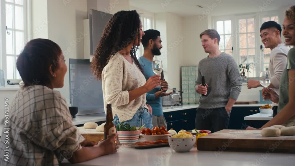 Multi-cultural group of young friends at home in kitchen celebrating with drinks making food for party - shot in slow motion Multi-cultural group of young friends at home in kitchen celebrating with drinks making food for party - shot in slow motion