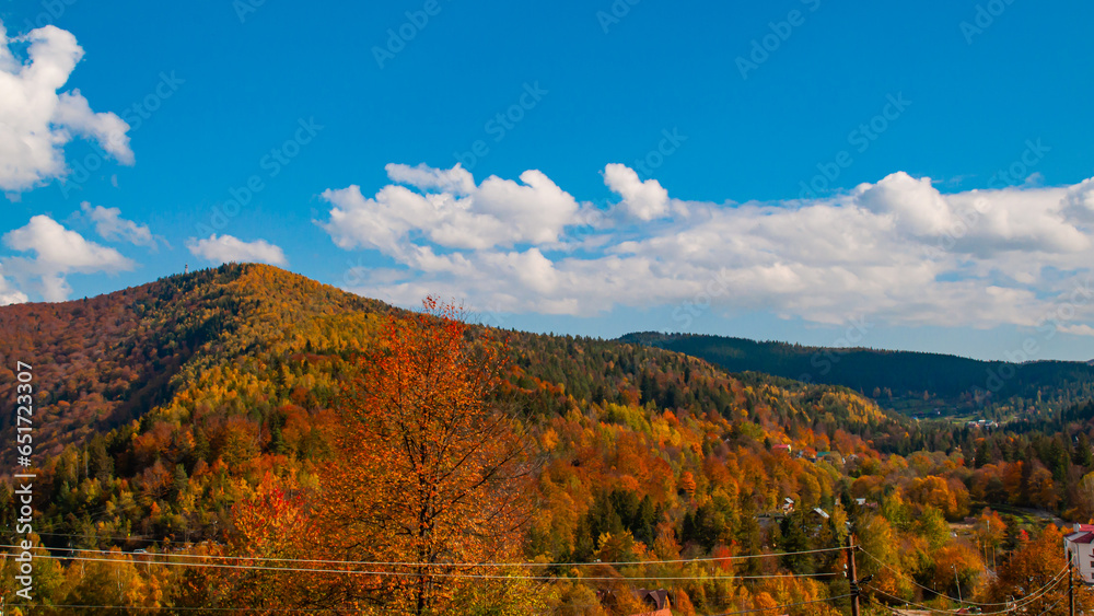Autumn mountain landscape against the blue sky with white clouds