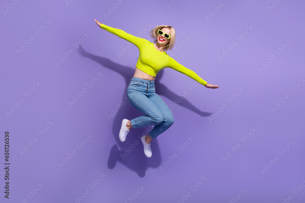 Full length photo of cheerful glad girl wear trendy clothes have fun fly air empty space isolated on purple color background