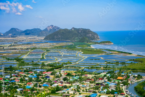 Aerial panorama of Thailand's Khao Sam Roi Yot National Park, there is a well-known tourist destination with views of the sea, limestone mountain, and a farm. © Thananchanok