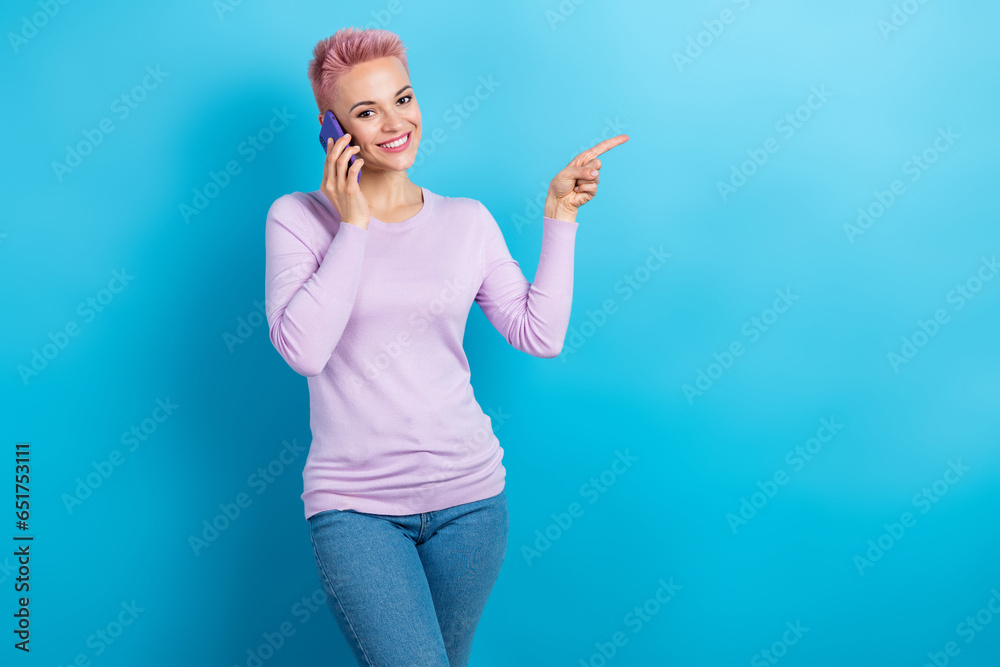 Fototapeta premium Photo of cheerful person wear trendy sweatshirt talk on smartphone indicating at offer empty space isolated on blue color background