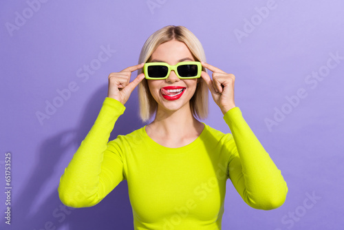 Photo of funky lovely girl wear stylish yellow shirt fingers tousching glasses tongue lick lips isolated on violet color background