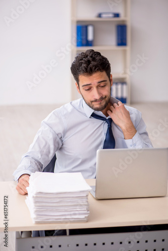 Young male employee and too much work in the office