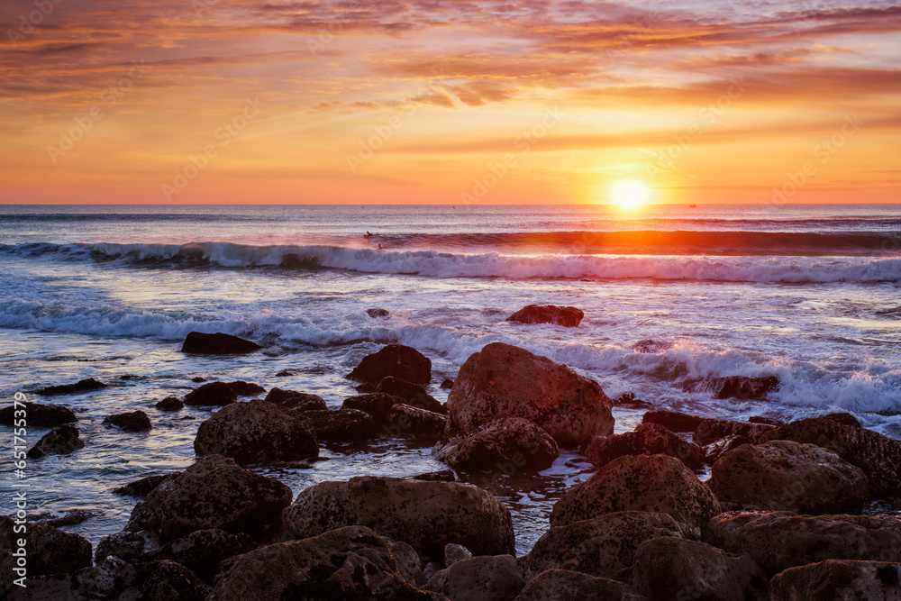 Atlantic ocean sunset with waves and rocks at Costa da Caparica, Portugal