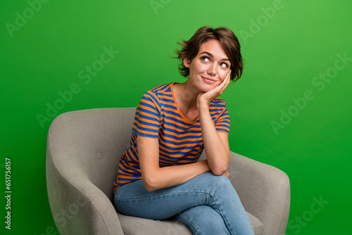 Photo of gorgeous minded lady sit cozzy chair arm touch cheek look empty space isolated on green color background photo