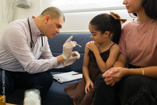 Pediatrician giving a vaccine to a little girl at home