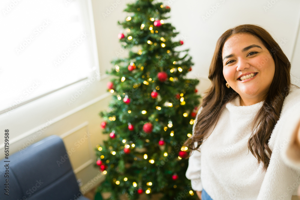 Attractive obese woman taking a selfie with her christmas tree Attractive obese woman taking a selfie with her christmas tree