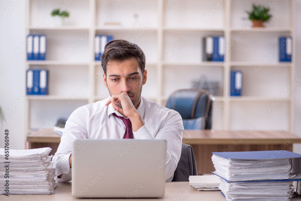 Young male employee and too much work at workplace Young male employee and too much work at workplace