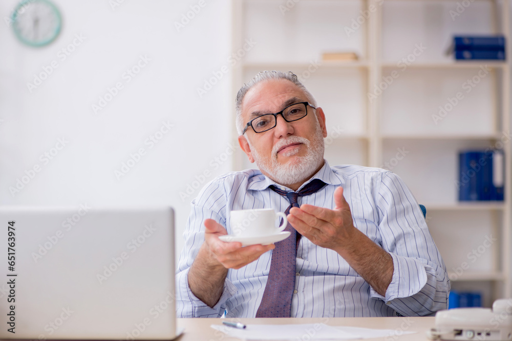 Old male employee drinking coffee during break Old male employee drinking coffee during break