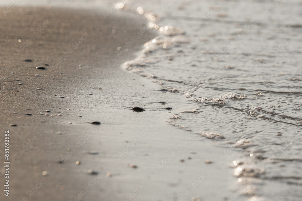 Soft ocean wave on sandy beach on sunset time, selective focus, textured pattern Soft ocean wave on sandy beach on sunset time, selective focus, textured pattern
