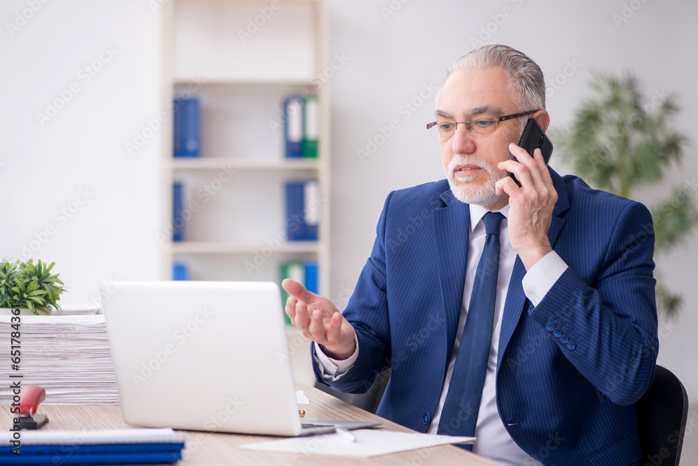 Old male employee working in the office Old male employee working in the office