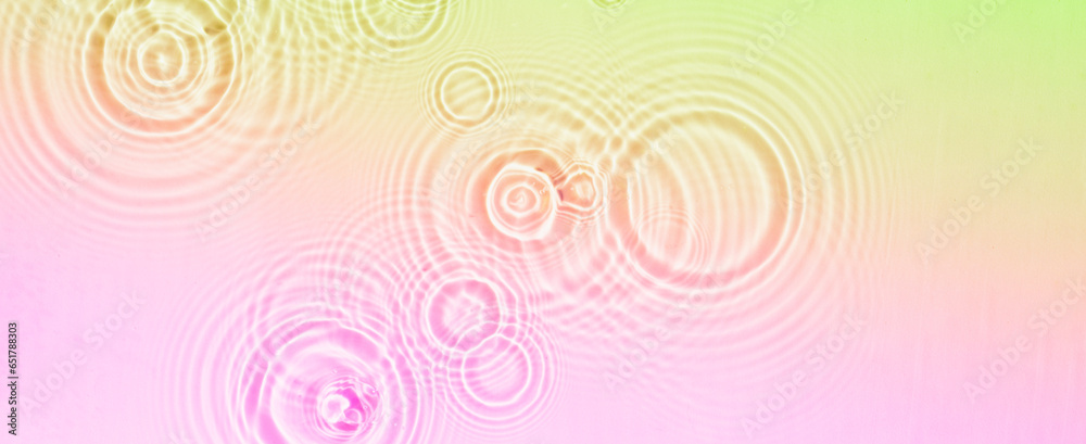Circles and waves on water of coral rainbow color in sunlight