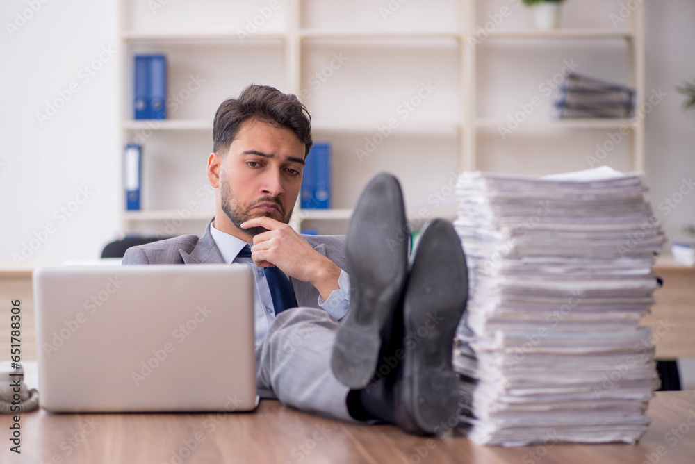 Young male employee and too much work in the office Young male employee and too much work in the office