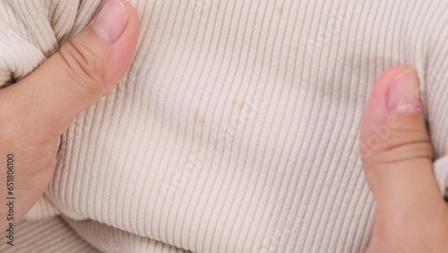 Close-up of woman looking at dirty stains on child's unwashable shirt. Dissatisfied young woman showing stains on t-shirt. Laundry problems