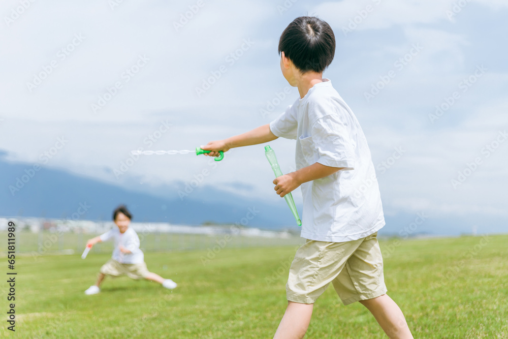 草原・公園でシャボン玉スティックで遊ぶ少年・兄弟・子供
