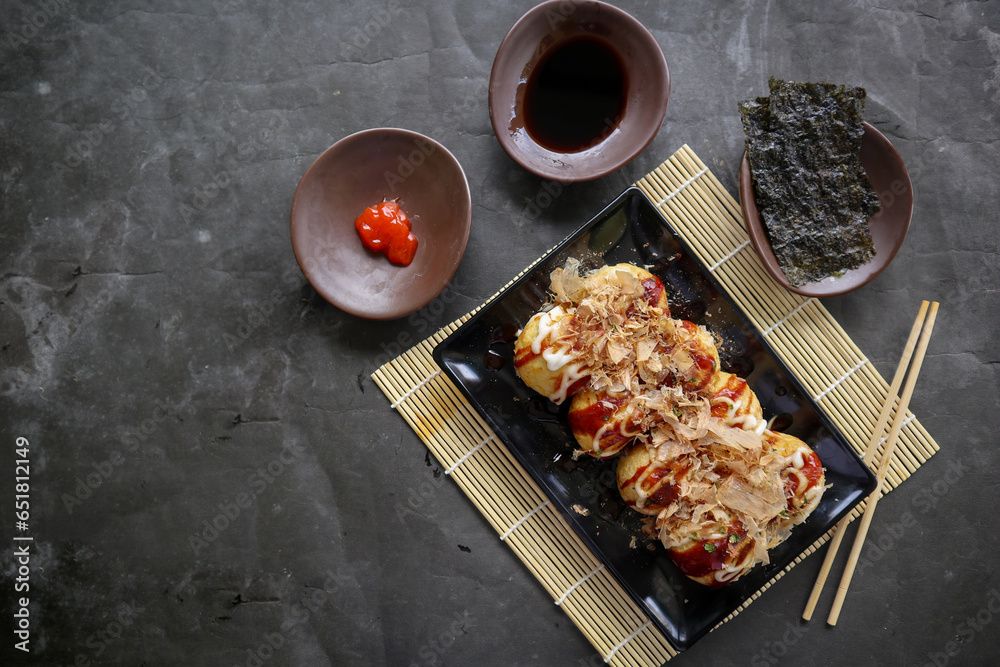 Naklejka premium Takoyaki is a Japanese food, made from wheat flour dough, octopus meat, or other fillings, served with sauce, mayonnaise and topping in the form of katsuobushi or wood fish shavings.