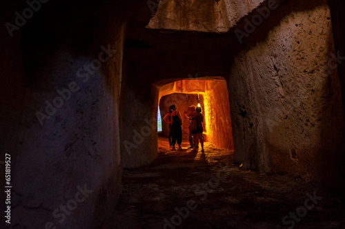 Gruppo di ragazze ascoltano la guida turistica in un antico tunnel sotterraneo a Siracusa photo