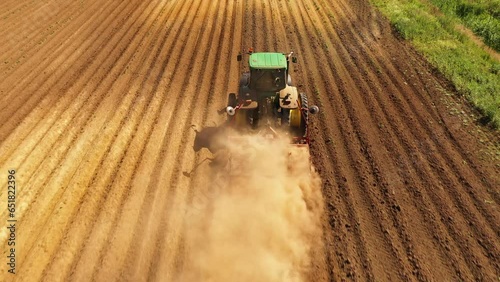 Tractor Hilling Potatoes with disc hiller in a potato field top view. Farmer in tractor preparing land with seedbed cultivator in farmlands
