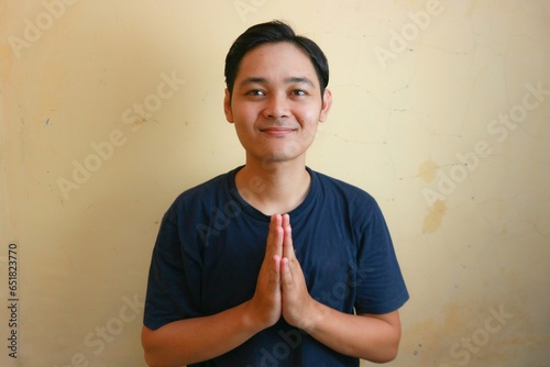 Excited Asian man wearing navy blue shirt with various expressions, on isolated yellow background