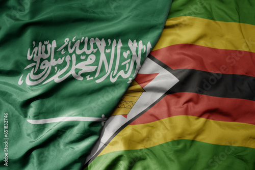 big waving realistic national colorful flag of saudi arabia and national flag of zimbabwe .