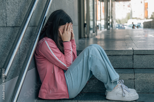 teenager girl sad and crying on the street stairs photo