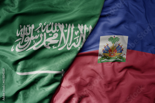 big waving realistic national colorful flag of saudi arabia and national flag of haiti .