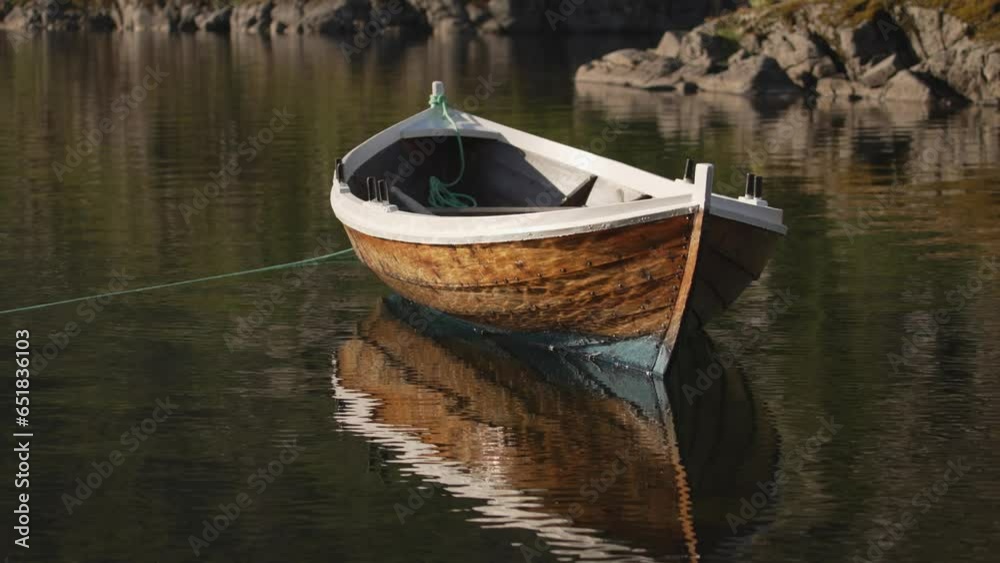 wooden rowing boat, harmoniously tied to a buoy, graces the calm surface of a Norwegian fjord, reflecting the rugged beauty of the mountains in the shimmering waters below wooden rowing boat, harmoniously tied to a buoy, graces the calm surface of a Norwegian fjord, reflecting the rugged beauty of the mountains in the shimmering waters below