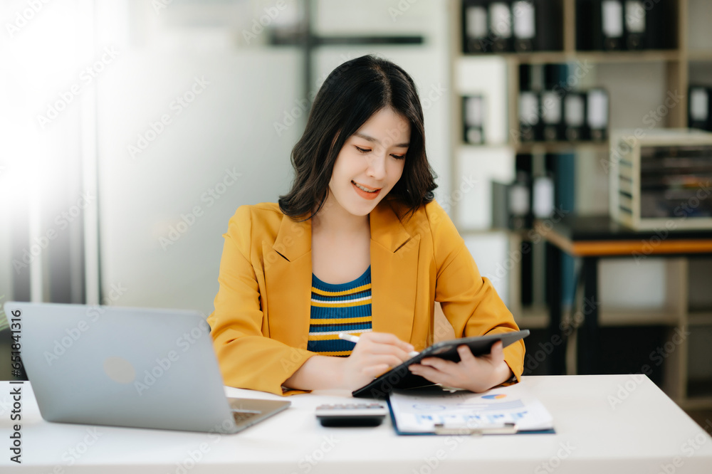 Young beautiful woman typing on tablet and laptop while sitting at the working table modern office. Young beautiful woman typing on tablet and laptop while sitting at the working table modern office.