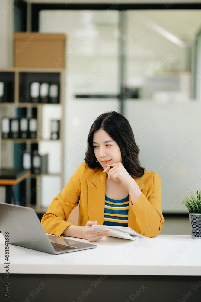 Young beautiful woman typing on tablet and laptop while sitting at the working table modern office. Young beautiful woman typing on tablet and laptop while sitting at the working table modern office.