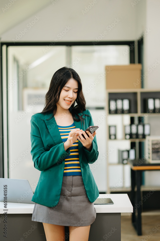 Confident Asian woman with a smile standing holding notepad and tablet at the office. Confident Asian woman with a smile standing holding notepad and tablet at the office.