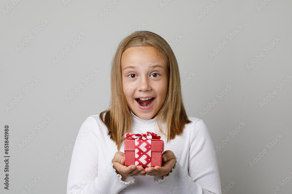 Portrait of happy surprised little child girl holding gift present box on white studio wall background. Cute excited kid Portrait of happy surprised little child girl holding gift present box on white studio wall background. Cute excited kid