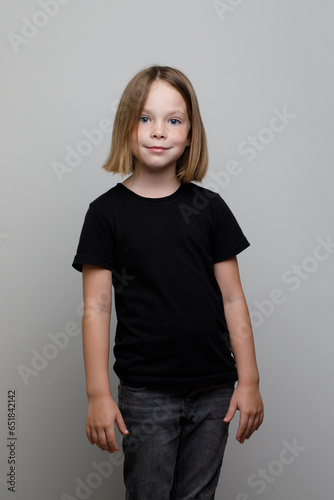 Little child girl wearing black t-shirt standing on white background. Happy Kid portrait