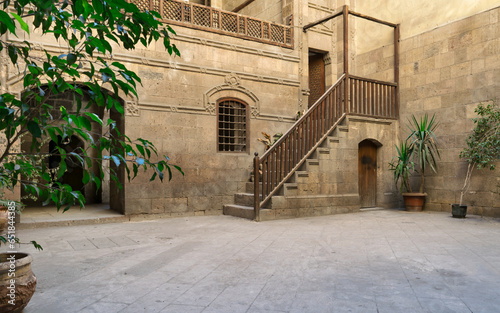 Courtyard of 15th century Ottoman era Zeinab Khatoun historic house, with stone bricks wall, wooden staircase leading up to the 2nd floor, and potted plants, Darb al-Ahmar district of Old Cairo, Egypt photo