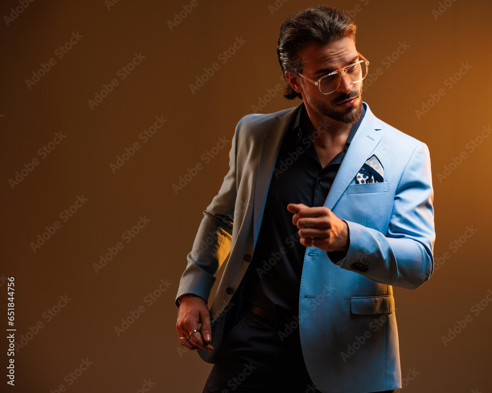 attractive man with glasses looking away while posing with arms in fashion pose attractive man with glasses looking away while posing with arms in fashion pose