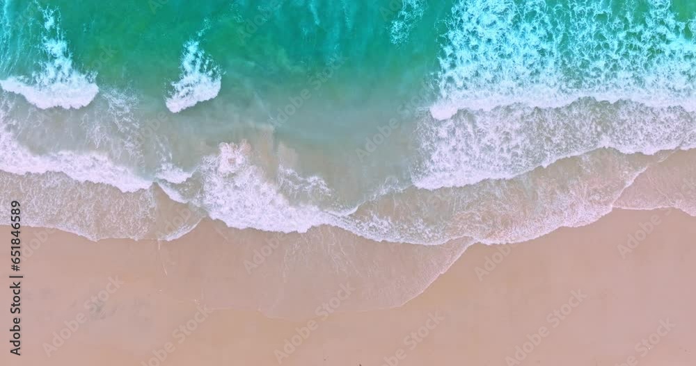 .aerial top view The waves slowly swept towards the shore..White foam waves in the bright green sea lapping on the white sandy beach..white bubble waves,and clear sand landscape. paradise beach..