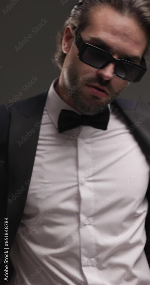 project video of cool stylish guy with sunglasses pulling and arranging tux jacket, turning and posing in a cool way on grey background project video of cool stylish guy with sunglasses pulling and arranging tux jacket, turning and posing in a cool way on grey background