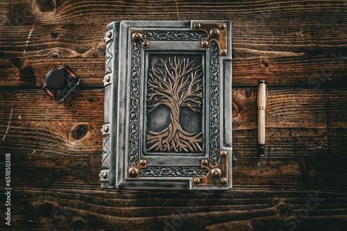 Old weathered white leather book with gilded tree of life captured on old wooden table