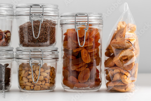 food storage, healthy eating and diet concept - close up of jars with dried fruits, seeds and nuts on table