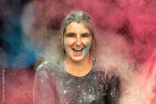 Portrait of a woman laughing between colorful powder