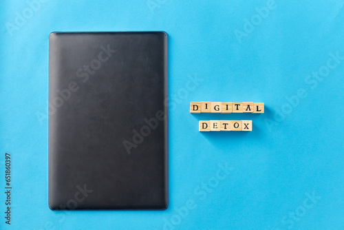 digital detox and technology concept - tablet pc or laptop computer and wooden toy block or stamps on blue background