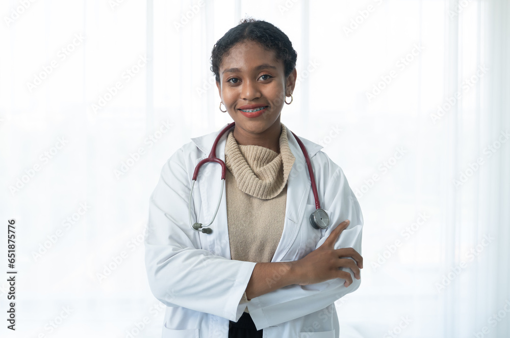 Happy young beautiful African American female doctor in white medical coat with stethoscope standing with crossed arms and smiling on white background Happy young beautiful African American female doctor in white medical coat with stethoscope standing with crossed arms and smiling on white background