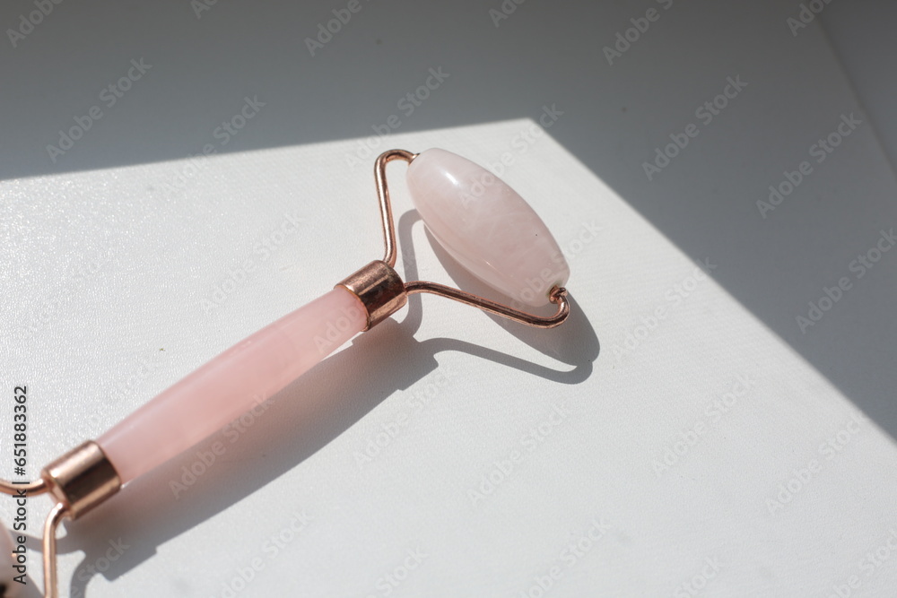 Pink face roller on white background with shades.