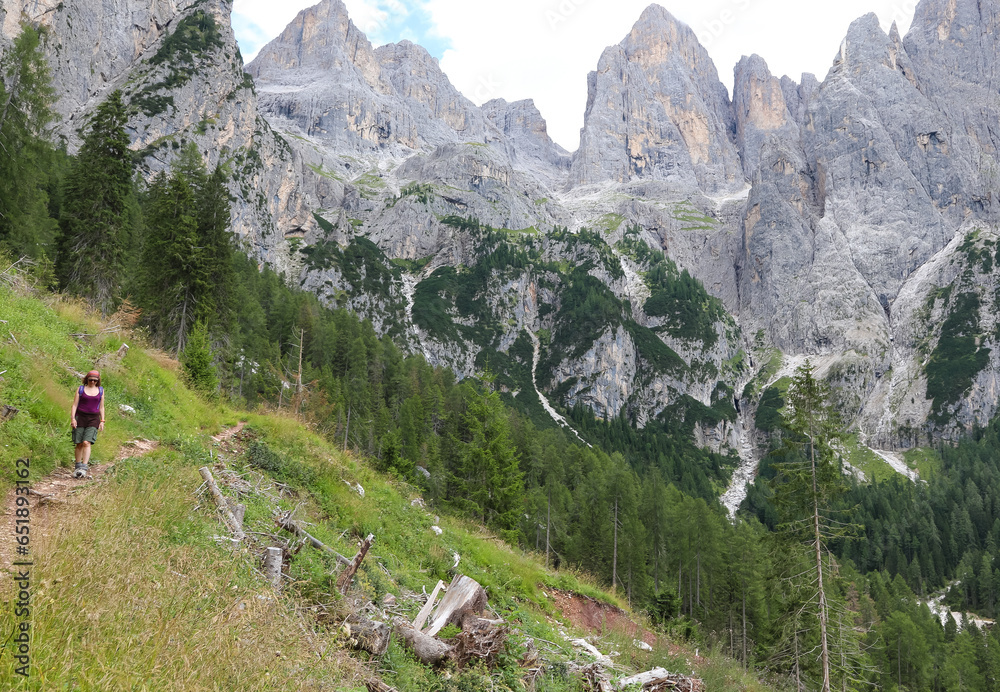 Young woman hiker walks on trail on European alps in Italy