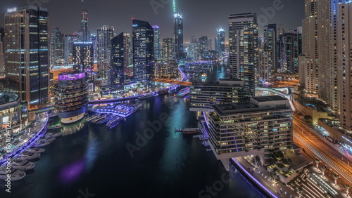 Aerial view to Dubai marina skyscrapers around canal with floating boats night