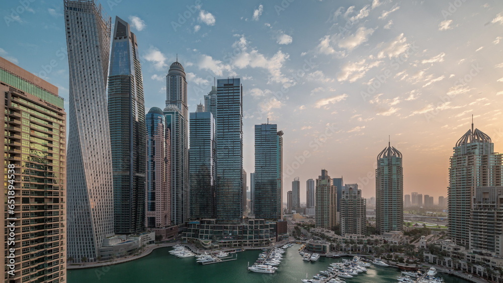 Fototapeta premium Dubai marina tallest skyscrapers and yachts in harbor aerial night to day.