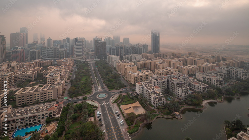 Fototapeta premium Skyscrapers in Barsha Heights district and low rise buildings in Greens district aerial night to day.