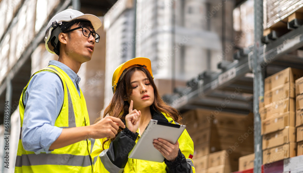 Fototapeta premium Asian two engineer team shipping order detail on tablet check goods and supplies on shelves with goods background inventory in factory warehouse.logistic industry and business export