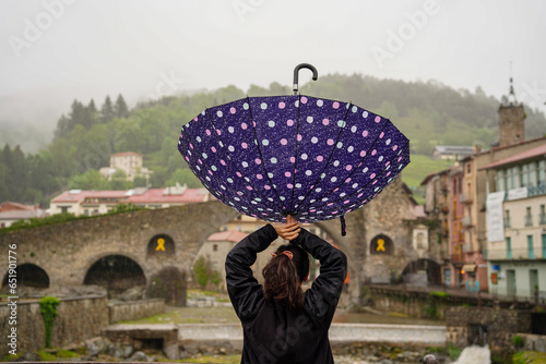 rear view of funny woman tourist holding an upside down umbrella in camprodon in winter. happiness for water after the drought photo