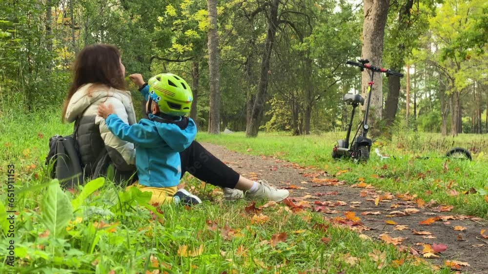 happy mother playing with little son on a walk in autumn park, mother with child little boy on electric scooter happy mother playing with little son on a walk in autumn park, mother with child little boy on electric scooter